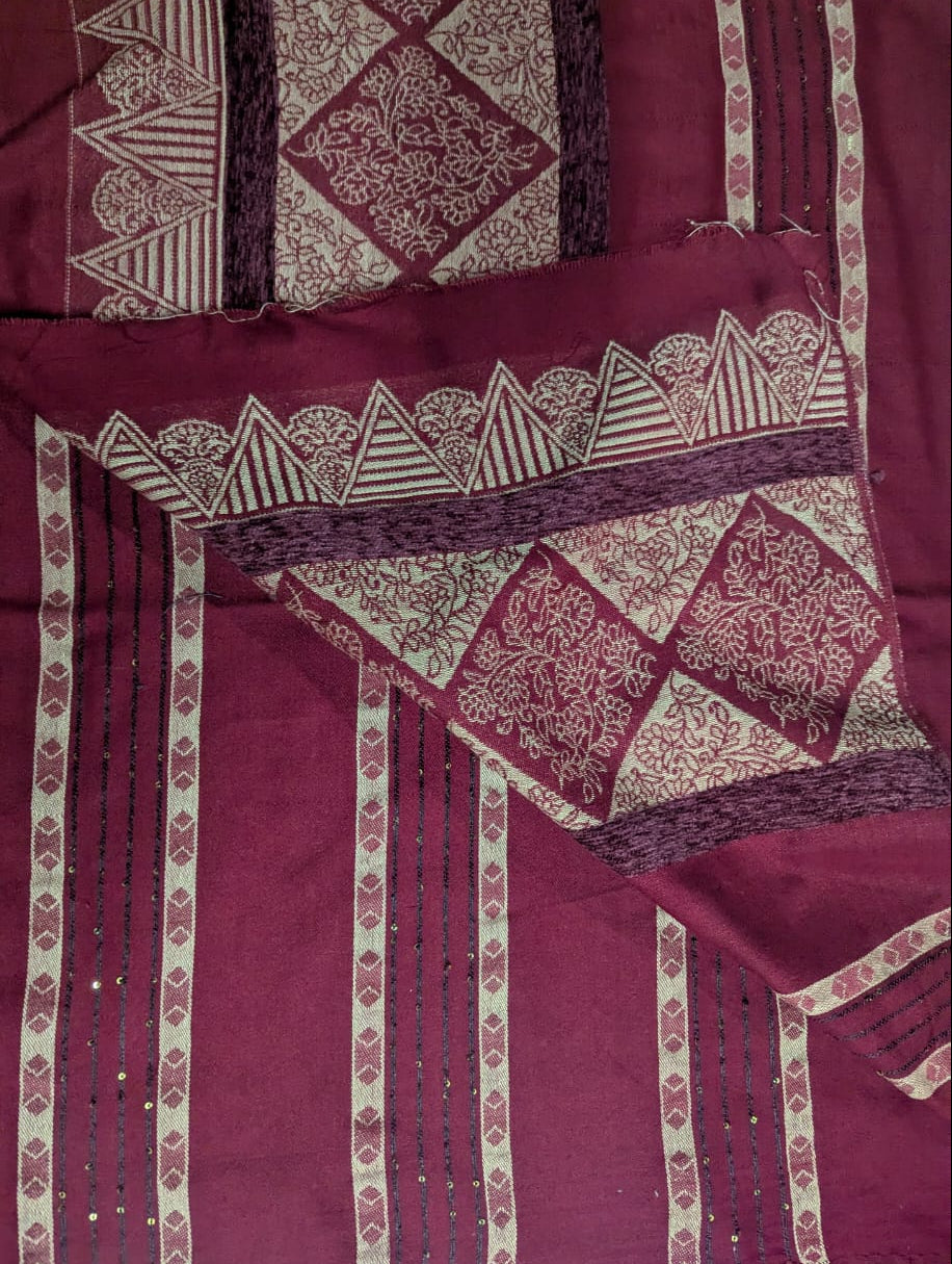 Maroon fabric with intricate gold patterns on a light blue background